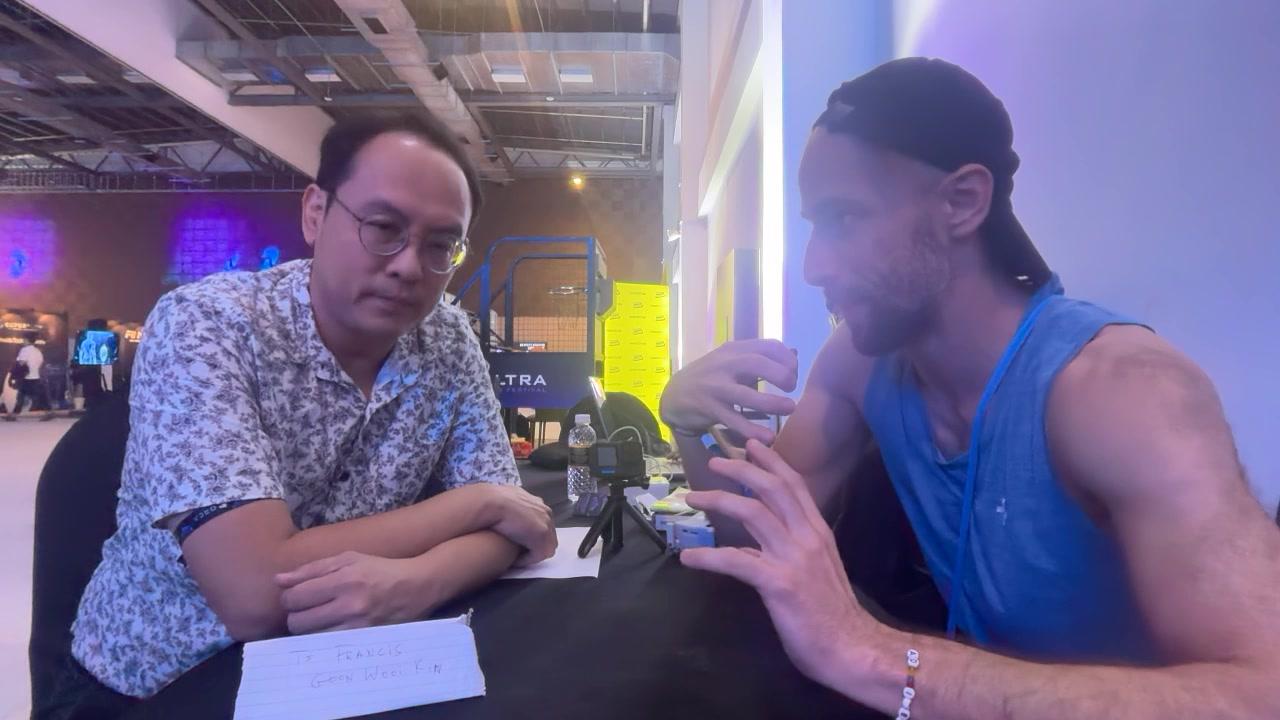 Francis Goon and Konrad talking across a table at the Ultra Web3 festival